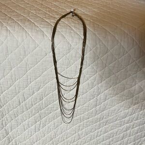 This beautiful necklace is gold and has multiple chains around each other.